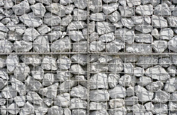 The texture of the wall of small gray stones under iron mesh. Natural stone wall texture photo, stone background , stone floor texture, grey floor in the garden, grey wall background.