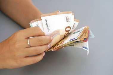 100-50 avroluk banknotları düşünen kadın elleri. Bir sürü paranın, bir sürü avronun elinde. İş kadını el ele tutuşup avro banknotlarını sayıyor.