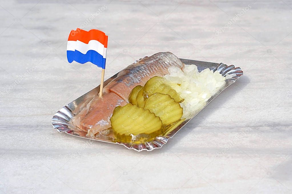 Dutch herring with onion and pickled cucumber. Traditional Dutch snack with raw herring with pickles. Dutch flag.