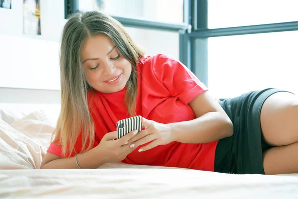 Boldog Lány Ágyon Otthon Egy Mobiltelefon Szexi Gyönyörű Ágyban Egy — Stock Fotó