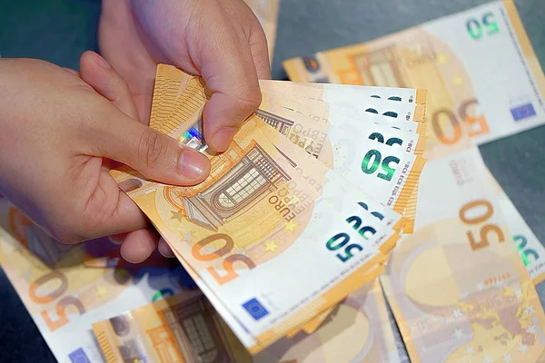 Human hands that consider 50-euro bills. In the hands of a lot of money, 50 denominations of euros