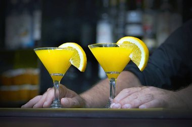 Barmen bir kokteyl otel barının istemciye verir. Taze kokteyl ile portakal. Alkollü, alkolsüz içki-içecek barda gece kulübüne karşı. Turuncu kokteyl bardak.