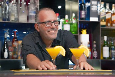 Barmen bir kokteyl otel barının istemciye verir. Taze kokteyl ile portakal. Alkollü, alkolsüz içki-içecek barda gece kulübüne karşı. Turuncu kokteyl bardak.