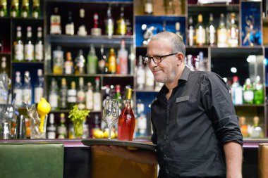 Bir şişe kırmızı şarap hote çubuğunun istemciye bir tepsi üzerinde şarap gözlüklü bir adam barmen taşır restoran. Hizmet kavramı.