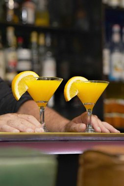 Barmen bir kokteyl otel barının istemciye verir. Taze kokteyl ile portakal. Alkollü, alkolsüz içki-içecek barda gece kulübüne karşı. Turuncu kokteyl bardak.