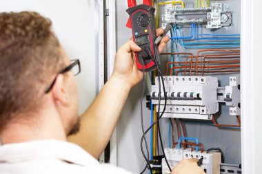Elektrikçi elektrik kabine multimetre ile gerilim ölçer. Elektrikçi elektrik kutusunda bir voltaj kontrol ediyor. Elektrik kumanda devre Endüstri/sanayii donatımı için düzeltilmesi.