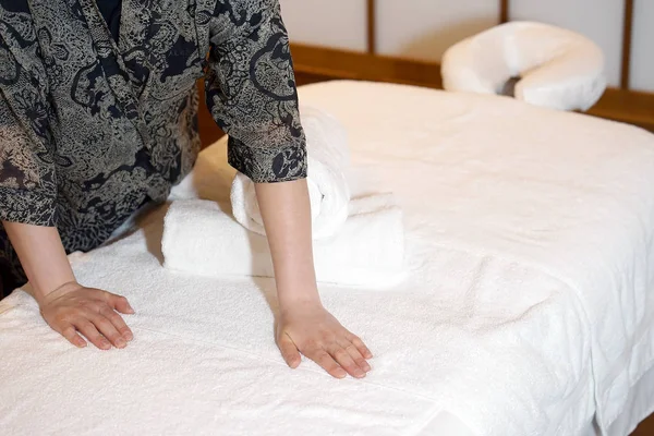The girl prepares a workplace massage bed in the spa for the reception of clients. The maid is preparing a room for the spa salon. Woman masseuse in the workplace. The concept of health and beauty.