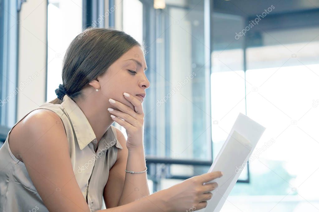 Woman reads negative news in a letter at home on the couch. The shaken business manager of received a notice of dismissal from the company, surprised. An agitated girl without joy.