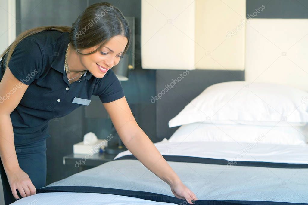Maid making bed in hotel room. Housekeeper Making Bed. Toning