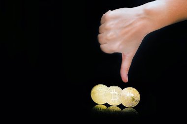 Kadın kolunu başparmak aşağı işaret göster. Başparmak aşağı el imzala. Siyah arka plan üzerine izole yakın çekim altın sanal para bitcoin. Fiziksel Bitcoin. Kripto Döviz Ticaret kavramı.
