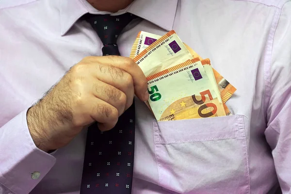 A businessman gives Euro a bribe to an employee in the office. Concept - corruption. Giving a bribe. Money in hand. The concept of corruption and bribery