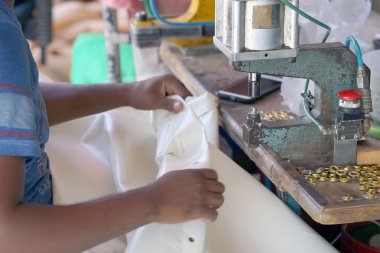 Erkekler Afrika eller katranlı muşamba içinde delikler yapmak. Terzi bir tuval üzerine dikiş makinesi diker. Seçici odak.