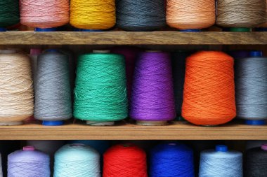 Bobinlere dikiş dikmek için renkli iplikler. Büyük renkli iplik makaraları yığını. İpin renkli iplik makaraları büyük sınıf, tekstil, arkaplan