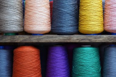 Bobinlere dikiş dikmek için renkli iplikler. Büyük renkli iplik makaraları yığını. İpin renkli iplik makaraları büyük sınıf, tekstil, arkaplan