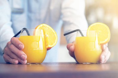 Barmen iki bardak portakal suyu otel restoran istemciye verir. Garson sipariş iki portakal suyu için otel barının istemciye aktarır. Hizmet kavramı. Tonlama