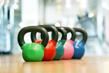 Renkli kettlebells üst üste bir spor salonunda ahşap zemin üzerinde. Spor salonunda kettlebells satırları.