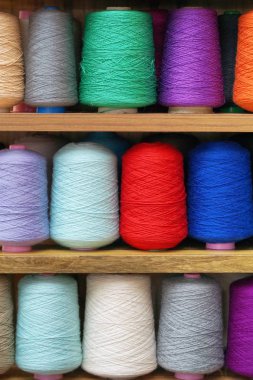 Bobinlere dikiş dikmek için renkli iplikler. Büyük renkli iplik makaraları yığını. İpin renkli iplik makaraları büyük sınıf, tekstil, arkaplan