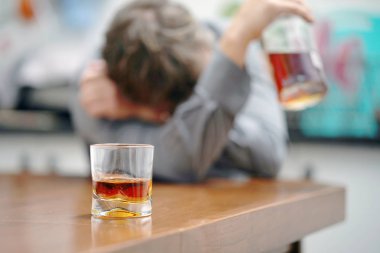 Bir bardak viski bir sarhoş adam arka plan üzerinde masada. Alkolik bir baba