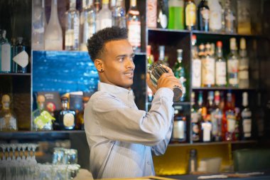 Bir shaker taze ve lezzetli bir kokteyl ile elinde tutan profesyonel barmen erkek. Barmen gibi o barın arkasında duran bir kokteyl shaker sallayarak bir müşteri için bir içki karıştırma. Yakın çekim. Tonlama.