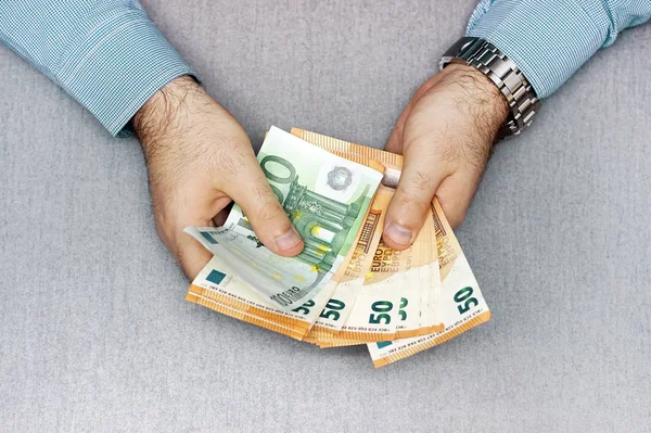 Human hands that consider 100, 50-euro bills. In the hands of a lot of money, 50 denominations of euros
