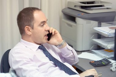 İş yerinde Evet iş adamı. Yakın çekim telefona cevap ve bir müşteri hizmetleri merkezi bir bilgisayar monitörü bakarak bir erkek ofis çalışanı. Otel resepsiyonist bilgisayar ve telefon kullanarak