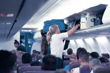 Hostes yolcular uçağın Kabin Bagaj koymak için yardımcı olur. Uçaktaki hostes. Seçici odak