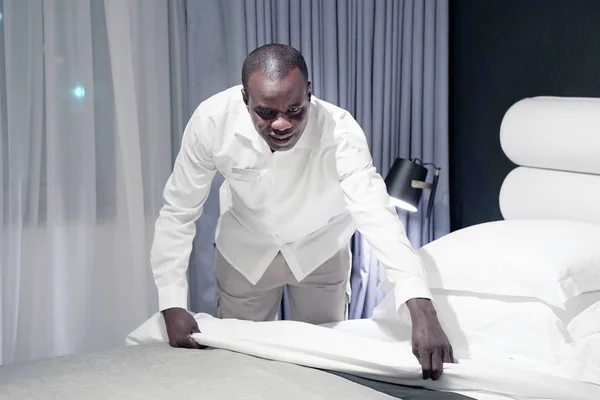 在酒店房间里铺床 工作人员女仆做床 非洲管家在铺床 — 图库照片