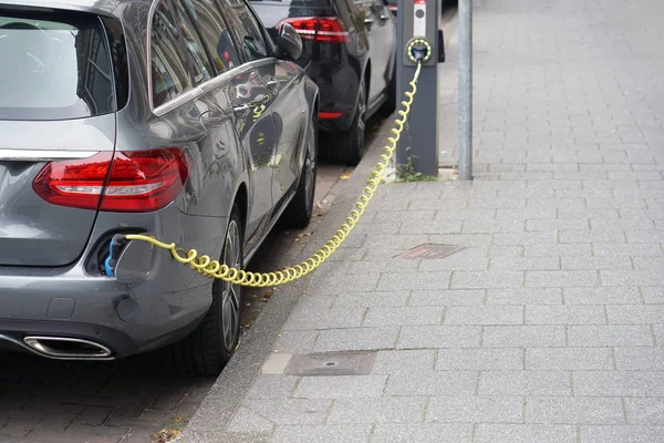 駅を充電する電気自動車を駐車場で充電する電気自動車 電気自動車充電中に差し込まれている電源のクローズ アップ — ストック写真