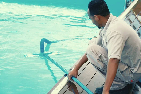 Hotel staff worker cleaning the pool