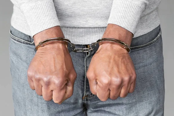 Criminal hands locked in handcuffs. Close-up view — Stock Photo, Image
