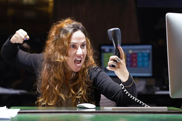 Mulher em stress em frente ao computador. Uma mulher está gritando para o telefone . — Fotografia de Stock