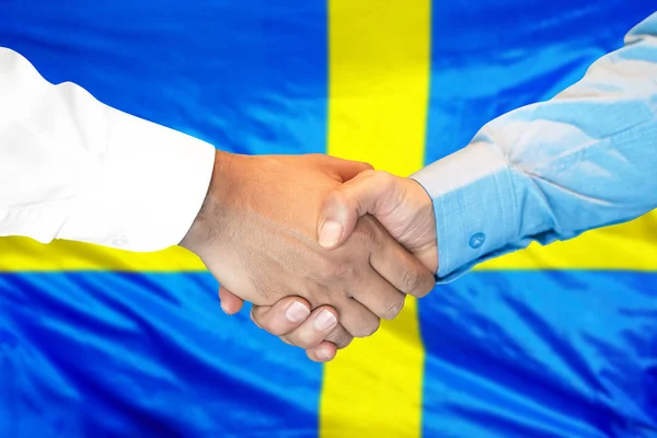 handshake on Swedish flag background.