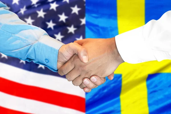 handshake on american and Swedish flag background.