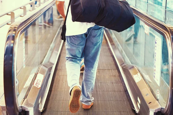 Ein Mann mit Gepäck auf einer waagerechten Rolltreppe — Stockfoto