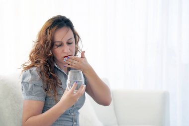 Kadın bir hap acıdan içiyor.