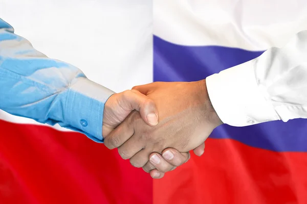 Рукопожатие на фоне флага Польши и России . — стоковое фото