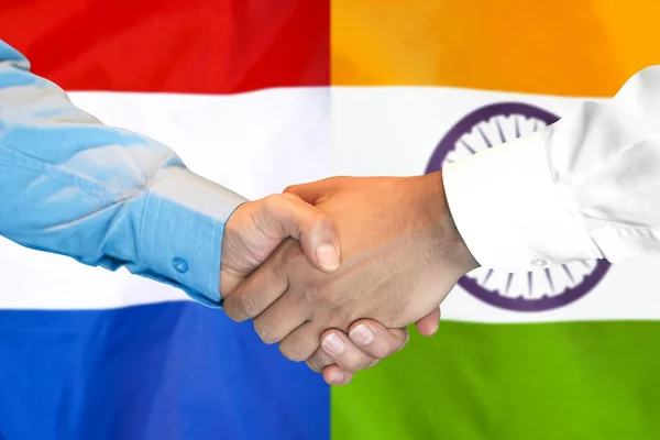 Handskakning om Indien och Nederländerna flagga bakgrund. — Stockfoto