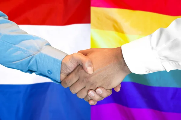 Apretón de manos en el fondo de la bandera gay y holandesa LGBT . —  Fotos de Stock