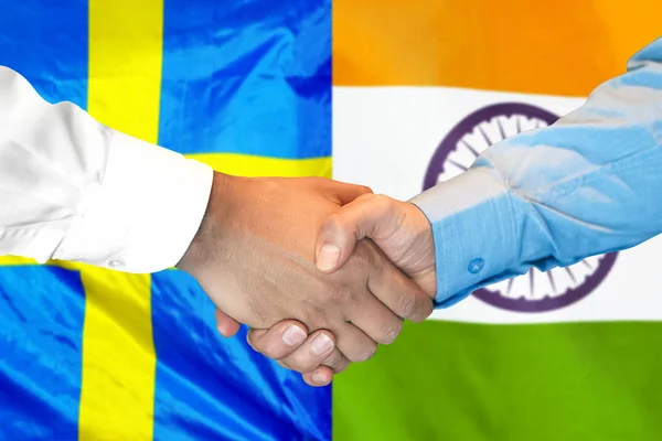 handshake on India and Sweden flag background.