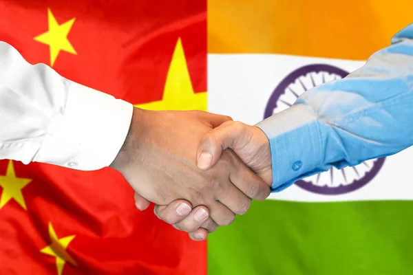 handshake on India and China flag background.