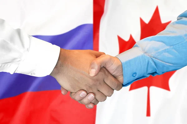 Apretón de manos en el fondo de la bandera de Canadá y Rusia . — Foto de Stock