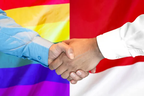Stretta di mano su gay LGBT e Monaco bandiera sfondo . — Foto Stock