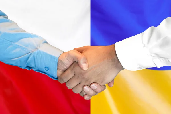 handshake on Poland and Ukraine flag background.