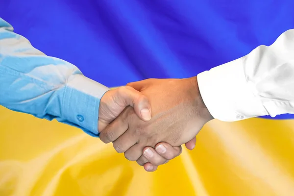 Apretón de manos sobre fondo de bandera de Ucrania . — Foto de Stock