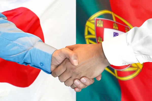 Podání ruky na pozadí vlajky Portugalska a Japonska. — Stock fotografie