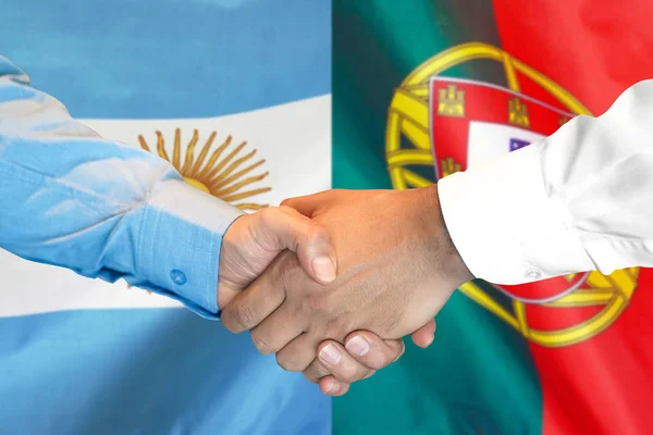 Рукопожатие на фоне флага Португалии и Аргентины . — стоковое фото