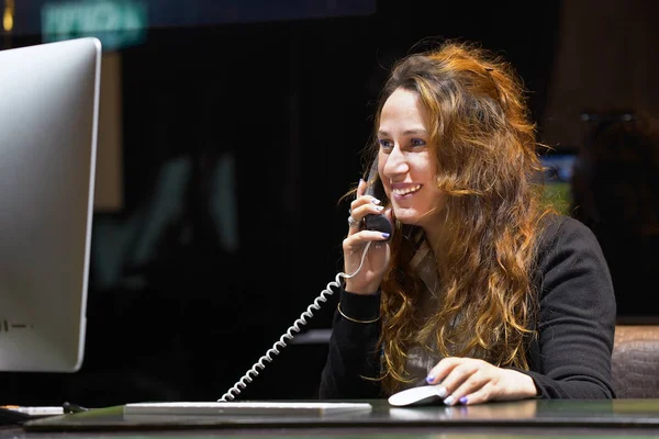 Женщина, сидящая за столом и отвечающая на телефонный звонок . — стоковое фото