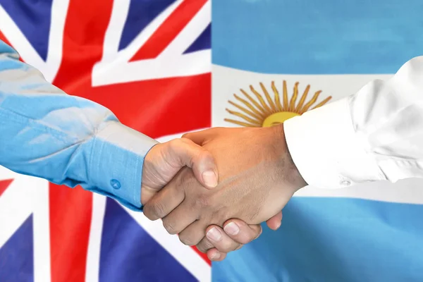 Apretón de manos en el fondo de la bandera del Reino Unido y Argentina . —  Fotos de Stock