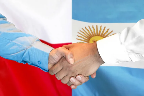 Apretón de manos sobre fondo de bandera de Argentina y Polonia . — Foto de Stock