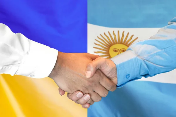Handskakning om Argentina och Ukraina flagga bakgrund. — Stockfoto